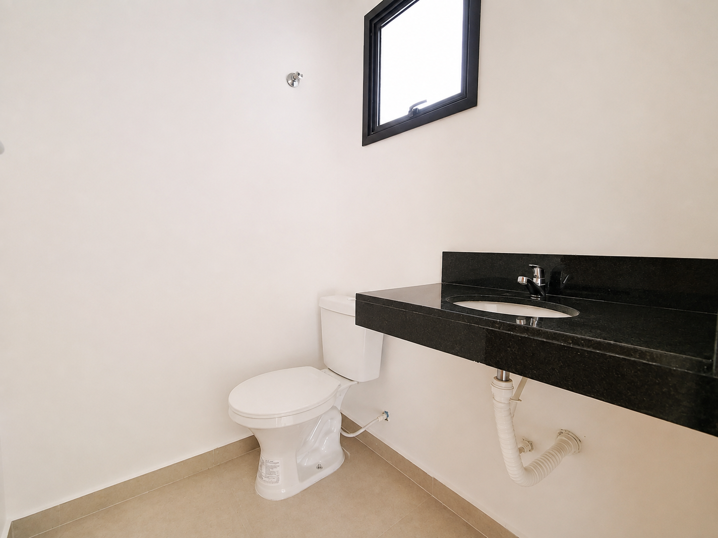 Lavabo com bancada em granito preto e janela basculante